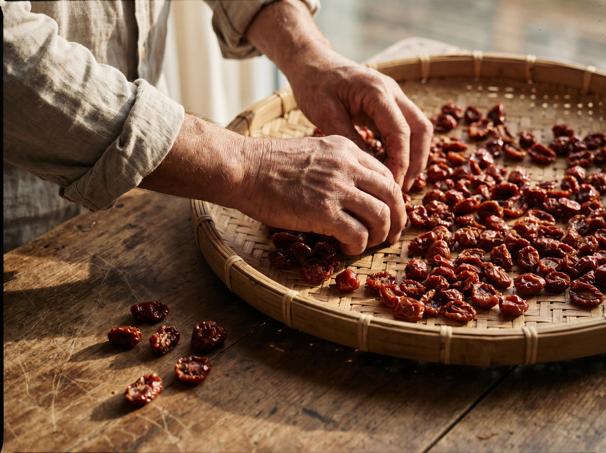 Weathered hands sorting dried cherry tomatoes on a flat woven sieve